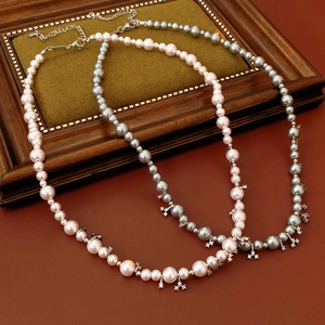 Detail of pink and silver-grey pearl necklaces with zircon charms on vintage background
