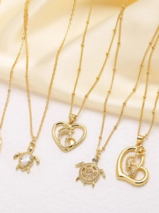 Dettagli dei ciondoli a cuore e tartaruga placcati oro 18k su sfondo di seta