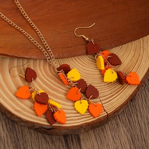 Detail of colorful autumn maple leaf pendant necklace and long tassel earrings on wood