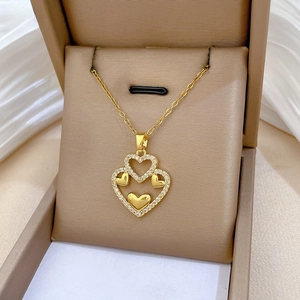 Close-up of golden double-layer heart necklace with white zirconia crystals on a silk cloth