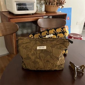 Detailed close-up of elephant and floral jacquard makeup bags on a wooden desk
