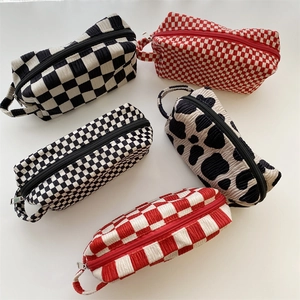 Detail of corduroy makeup bags with checkered and cow prints and zipper handle closure