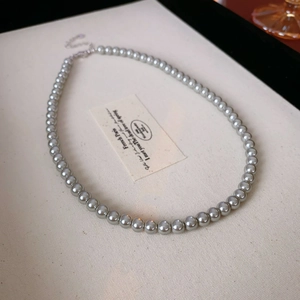 Nahaufnahme der silbergrauen Perlenkette mit Metallverschluss auf schlichtem Grund