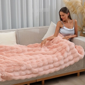 Close-up of thick pink faux rabbit fur blanket with soft plush texture on a sofa