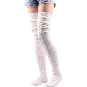 Detail of white cable knit over-knee leg warmers showing thick braided texture on model