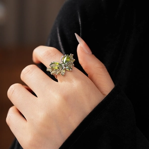 Gros plan détaillé d'une bague papillon en argent avec une pierre gemme verte sur un doigt