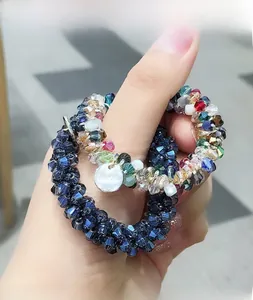 Détail de chouchous élastiques perlés avec perles de cristal et breloques portés au poignet