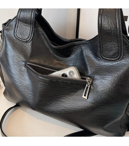 Detail view of large black tote bag featuring a functional back zipper pocket for a phone
