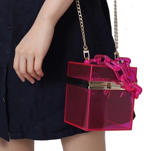 Detail of pink transparent acrylic box clutch with gold metal frame and thick chain strap