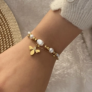 Bracelet double couche en perles avec pendentif abeille dorée et strass au poignet d'un mannequin