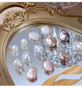 Baroque pearl pendants in multiple colors displayed on a luxury gold mirror tray