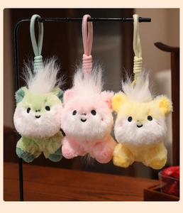 Detailed view of three colorful plush pony pendants hanging on a black display stand