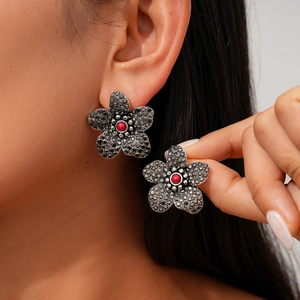 Gotische Blumenohrstecker mit schwarzen Kristallen und roter Perle an weiblichem Model