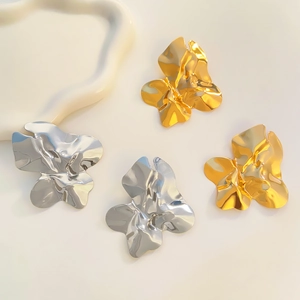 Dettaglio di orecchini a lobo a petalo ondulato in finiture metalliche oro e argento lucido
