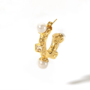 Macro shot of 18K gold plated C-shaped earring with white pearls and square zircon detail