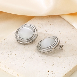 Detailed macro view of silver oval earrings with cat eye stone on a textured stone tray