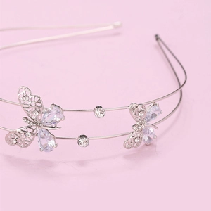 Close-up of silver zircon headband with hollow double butterfly design on pink background