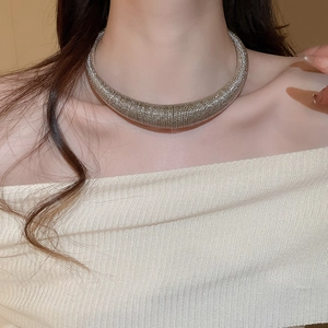 Detail of silver textured geometric necklace collar on model's neck near collarbone