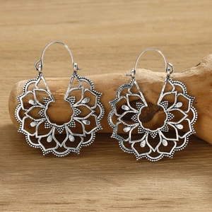 Detailed macro view of silver mandala earrings featuring intricate hollow metal patterns