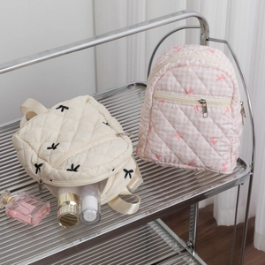 Detailed view of quilted makeup bags with cute embroidered bows and soft fabric texture