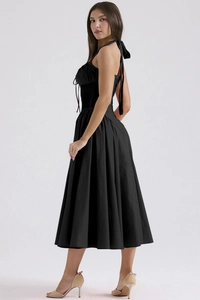 Detailed side view of black corset style halter neck dress with flared skirt design