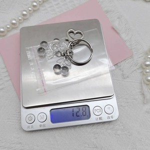 Detailed view of cherry pendant keychain weighing 12.8g on a digital scale