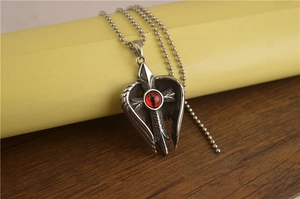 Gros plan du collier gothique en acier inoxydable avec œil rouge, ailes et pendentif croix
