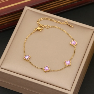 Elegant gold butterfly bracelet with purple crystals displayed on a beige jewelry box