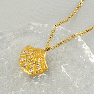 Detailed view of an 18K gold shell pendant necklace with sparkling diamond accents