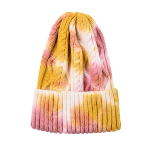 Close-up of thick cable knit texture and tie-dye pattern on winter cuffed beanie
