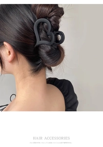 Close-up of a matte black heart-shaped hair claw clip styled on a woman's updo hairstyle