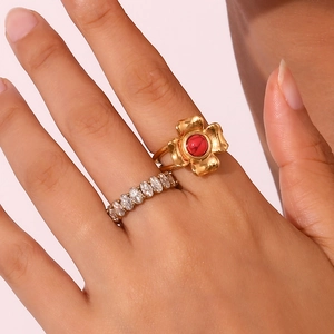 Detail of vintage 18K gold four-petal flower ring with red stone and silver crystal ring