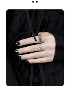 Detail of hollow silver mesh ring and green rock texture ring on model finger