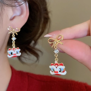 Macro detail of lion dance earrings featuring a bow, diamonds, and colorful enamel charms
