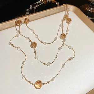 Detailed macro view of faceted amber crystal beads on a delicate gold beaded necklace