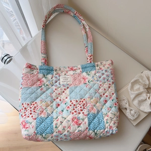 Detailed patchwork quilting and delicate floral patterns on a large cotton tote bag