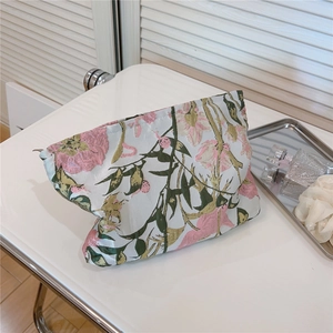 Detail of elegant floral jacquard makeup bag with pink flowers and green leaves pattern
