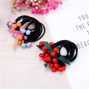 Pair of cherry and ribbon hair ties on a rustic wood background with dried flowers