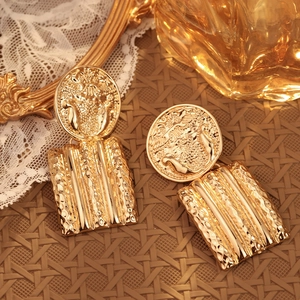 Chic vintage golden oversized textured drop earrings on natural woven background