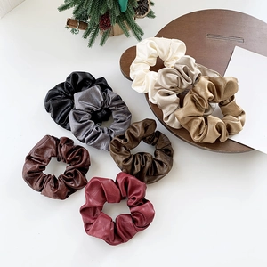 Set of 7 high-elasticity faux leather scrunchies in diverse colors on a minimalist display