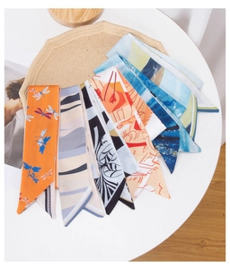 Flat lay of colorful assorted pattern silk scarves and hair ribbons on a wooden tray