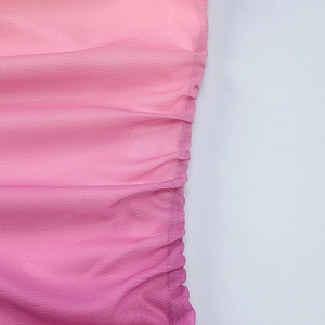 Détail macro de la texture en maille froncée rose dégradée sur une robe mi-longue moulante
