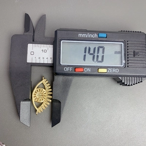 Macro shot of a gold evil eye pendant measured with digital calipers at 14.0 mm