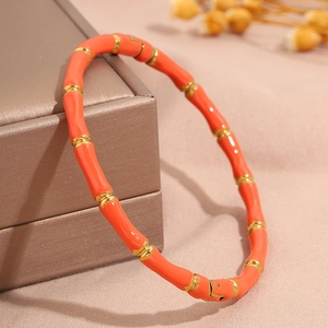 Detailaufnahme des orangefarbenen Emails und goldfarbenen Edelstahlarmbands