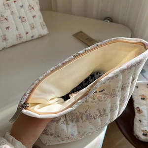 Close-up of quilted cotton makeup bag featuring rabbit prints and a smooth metal zipper