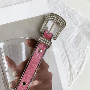 Dettaglio cintura glitter rosa con fibbia di strass e decorazioni in perline metalliche