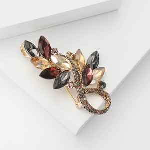 Macro shot of an elegant leaf-shaped brooch featuring colorful crystals on a metal base