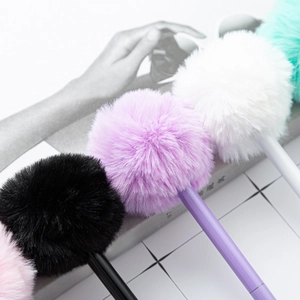 Cute plush ball pens with colorful fluffy pom poms and smooth plastic barrels on a magazine