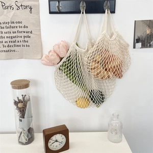 Détail de sacs filet en coton tissé beige avec fleurs et fruits dans un décor épuré