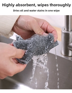 Close-up of hands wringing a thick grey charcoal fiber dishcloth over a kitchen sink